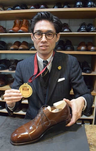 世界大会で磨いた靴とメダルを手にする西上悦弘さん＝13日、福岡市中央